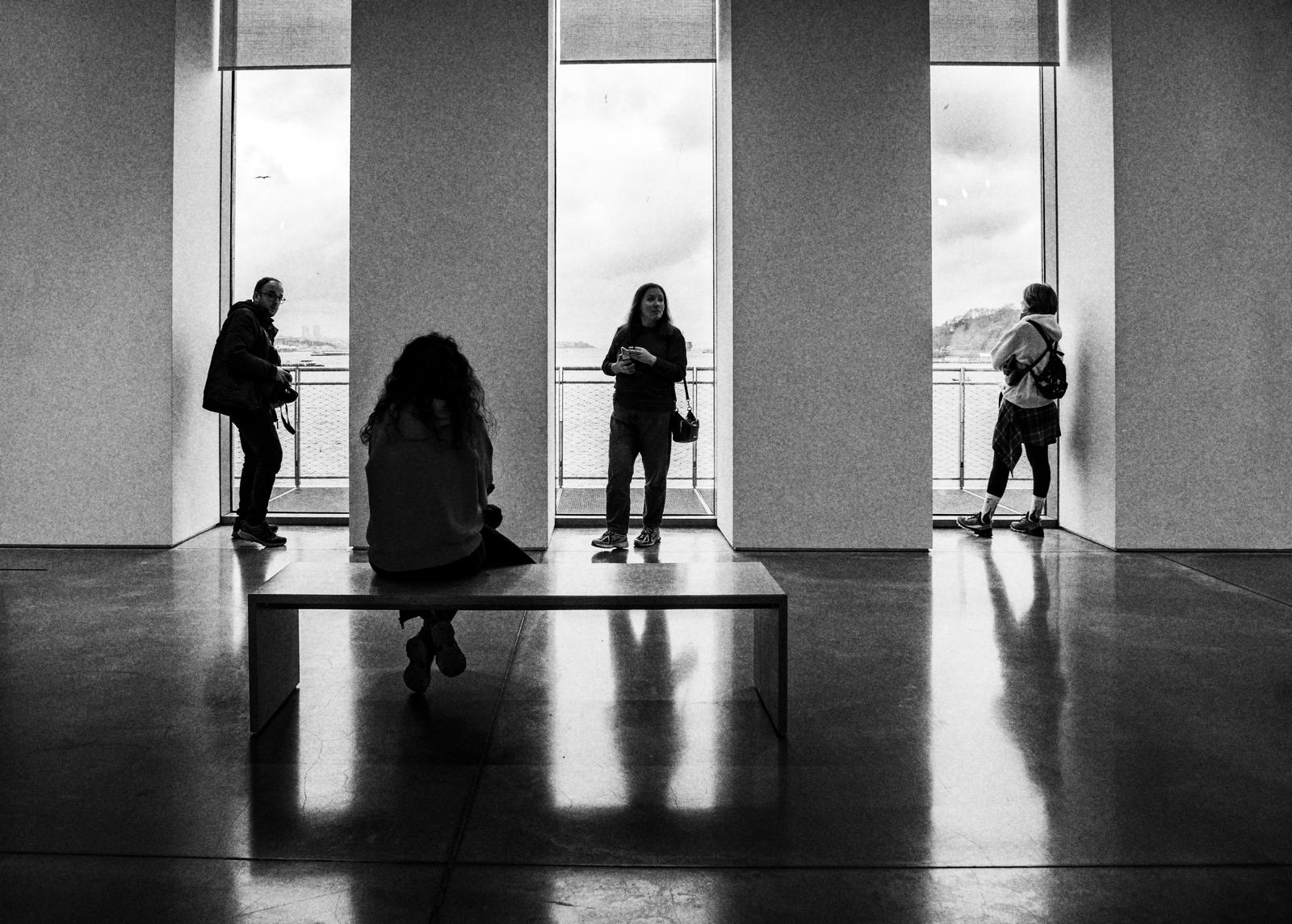 Visitantes de una sala de museo frente a los ventanales